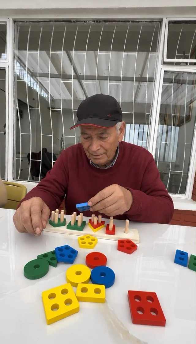 Hombre mayor encaja piezas geométricas de colores en una actividad de estimulación cognitiva