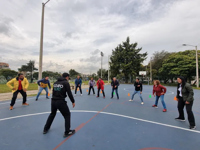Personas realizan ejercicios en grupo con un instructor en una cancha al aire libre