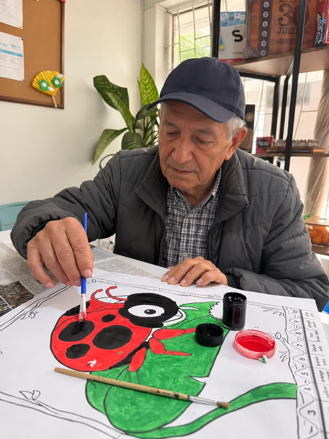 Hombre mayor pinta una mariquita con pinceles durante una actividad de arteterapia