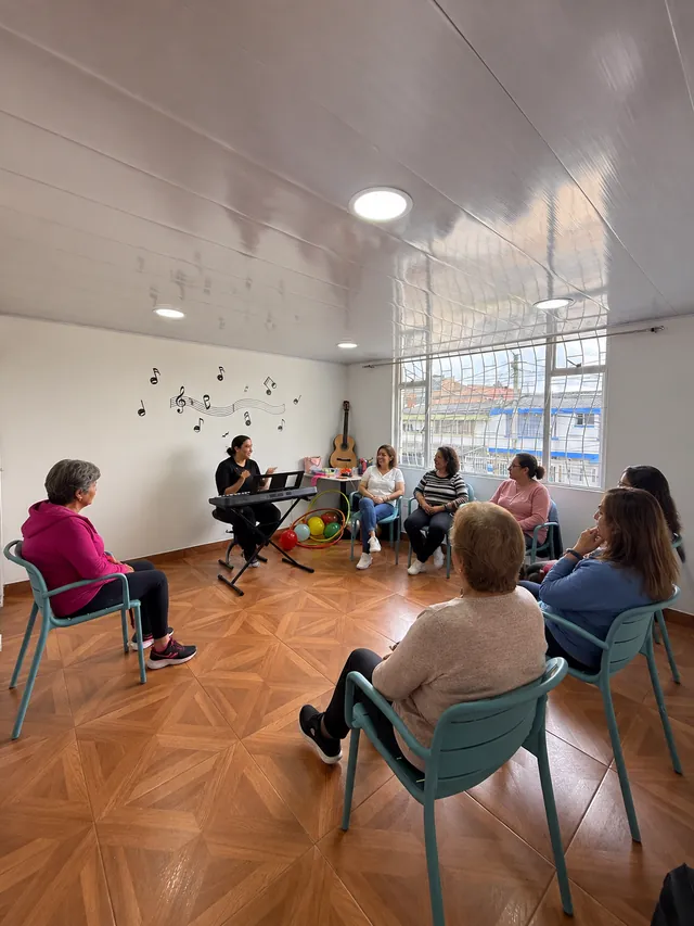 Mujeres reunidas en círculo participan en una actividad musical junto a un teclado