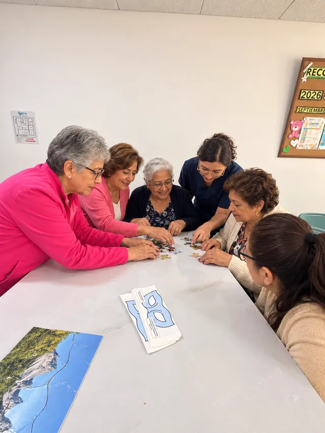 Mujeres mayores arman un rompecabezas en grupo con acompañamiento profesional