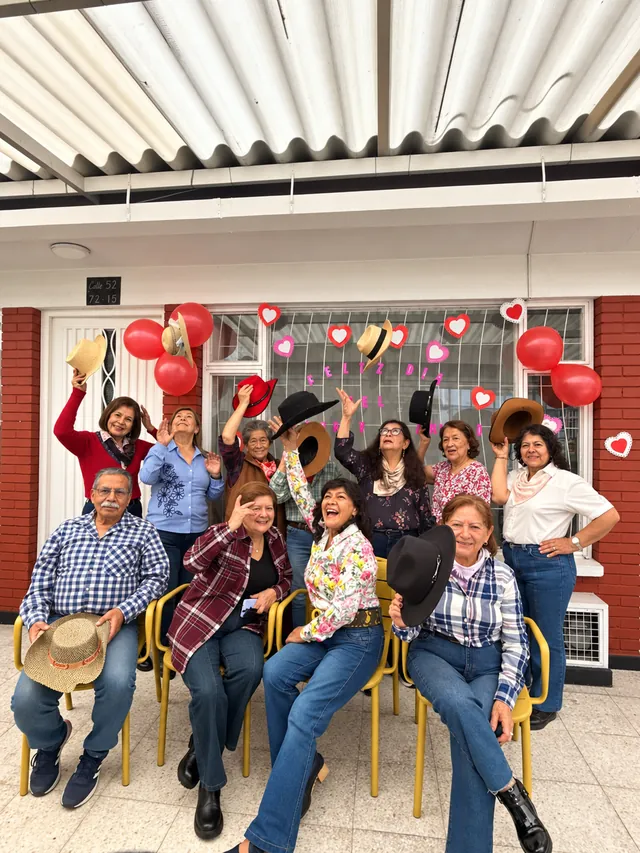 Personas mayores sonríen y levantan sus sombreros durante una celebración grupal